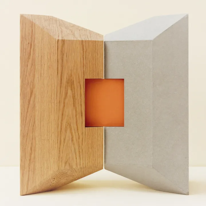 Dos materiales —roble y microcemento— encajados como una sola pieza, con un cubo de terracota en la unión: diseño y desarrollo, el agente entre ambos.